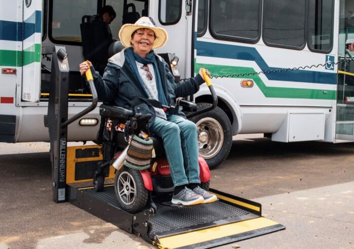 Woman in power wheelchair exiting bus off of lift