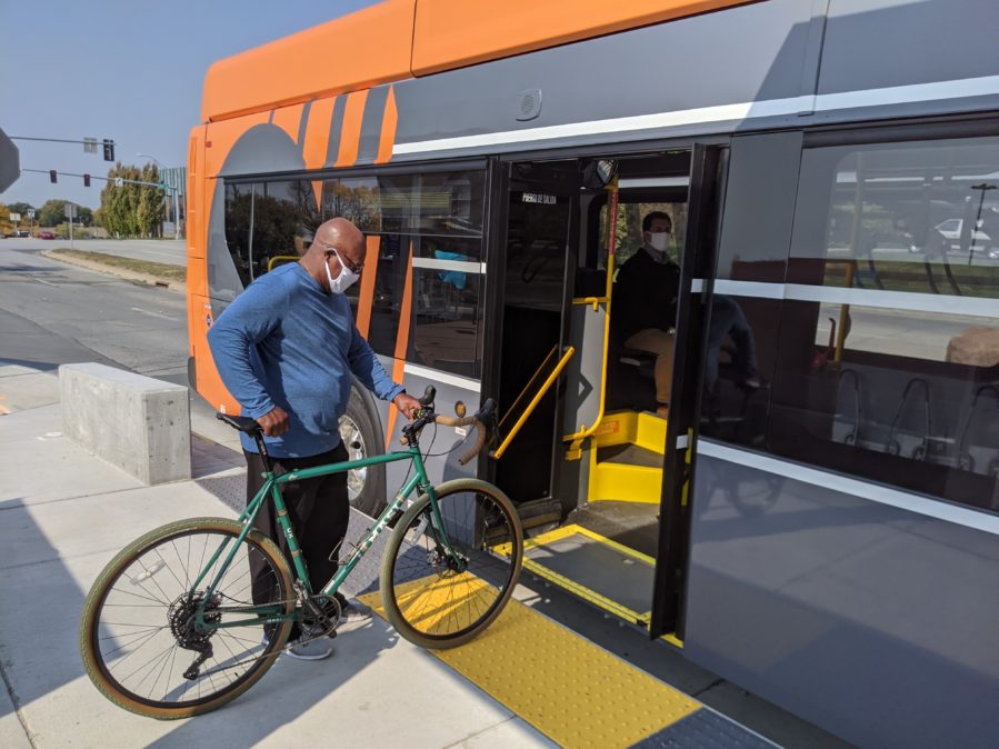 Bus rider bringing bicycle onboard an ORBT bus at the rear doors