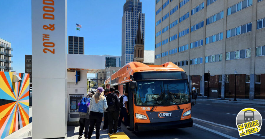 Photo of students boarding an ORBT bus at 20th & Dodge with a K-12 Rides Free logo in the bottom right corner