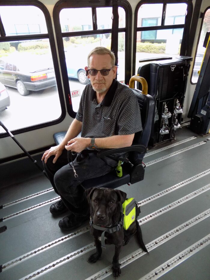 Individual seated on paratransit van with service dog
